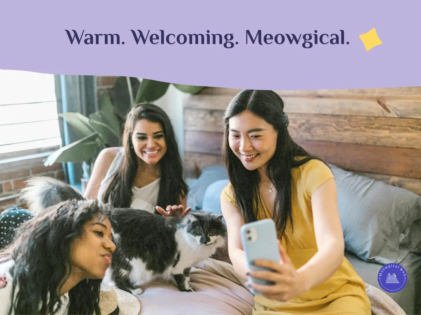 Three women smiling and taking a selfie with a cat on a cozy bed, representing warmth and connection in pet branding.
